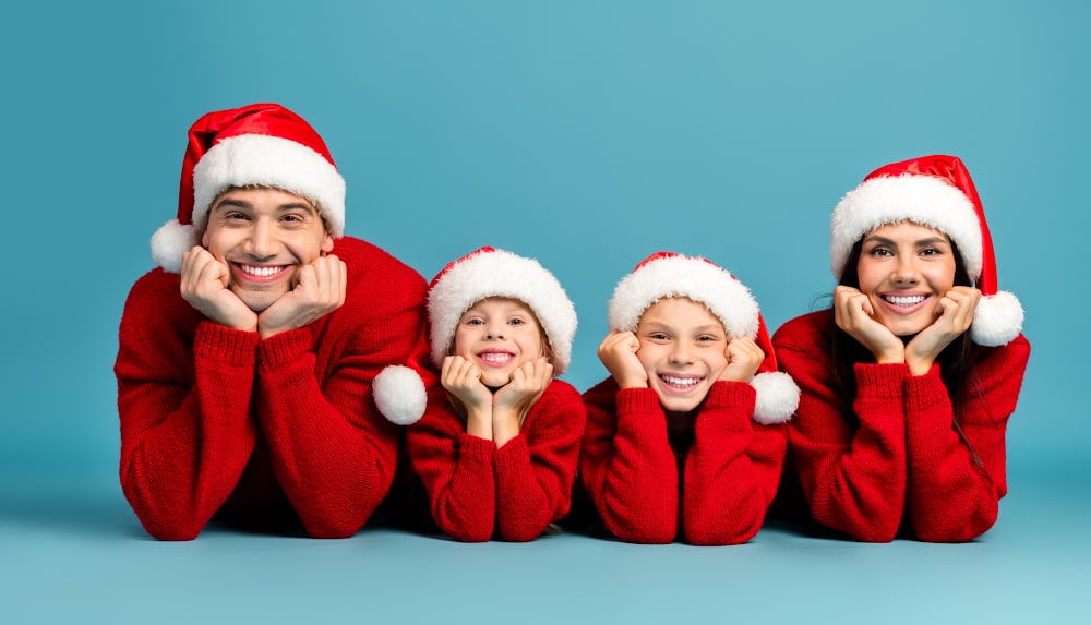 Festive family in red Christmas hoodies and Santa hats, seasonal tradition Family wearing Santa hats and red matching Christmas sweatshirts