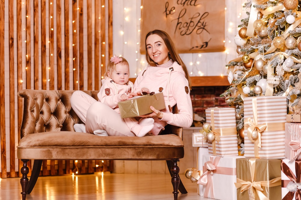 Mom and baby in festive matching hoodies, heartwarming holiday moment Mother and one-year-old child wearing matching Christmas hoodies, smiling